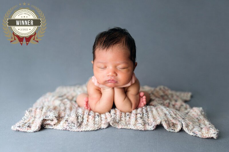 Newborn baby girl in froggy position during a studio newborn session.