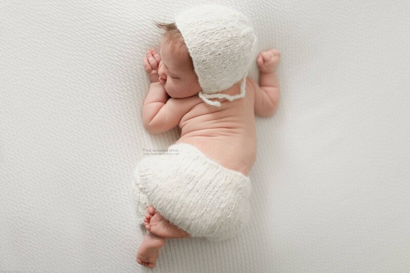 pretty baby girl sleeping in tushie up pose in white pants and white bonnet