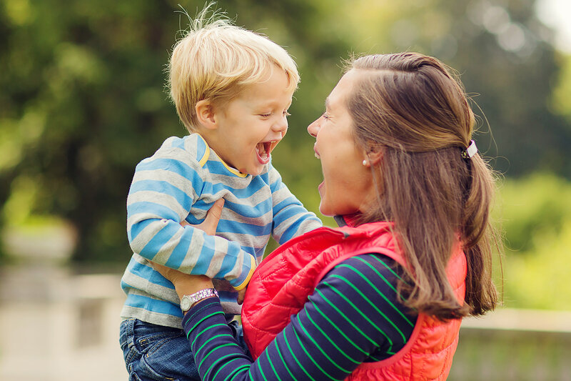 Mom and son in colorful stripes, looking at each other and laughing really big!