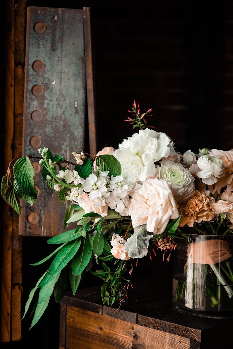 Lush ivory, orange and greenery bridal bouquet sitting on table