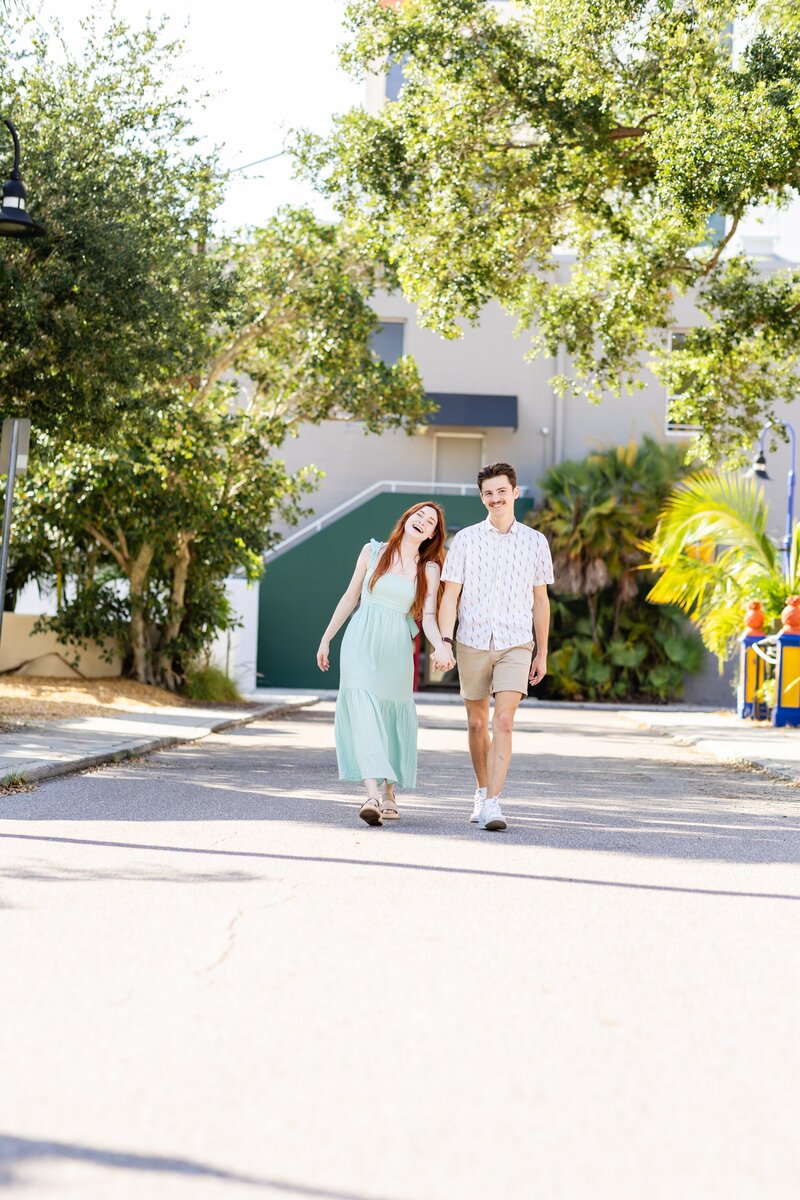 Young couple holding hands and walking down the street in Sarasota, FL