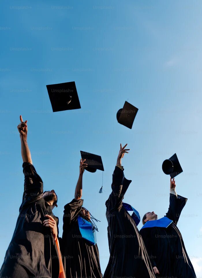 Four people at graduation throwing their caps. Showing college students who could benefit from group therapy in Manhattan or anywhere in New York. Get support from your peers and a group therapist as you approach post-college.