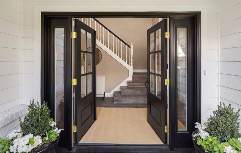 luxury entry way and front door with custom black painted wood double doors opened to wood stairway