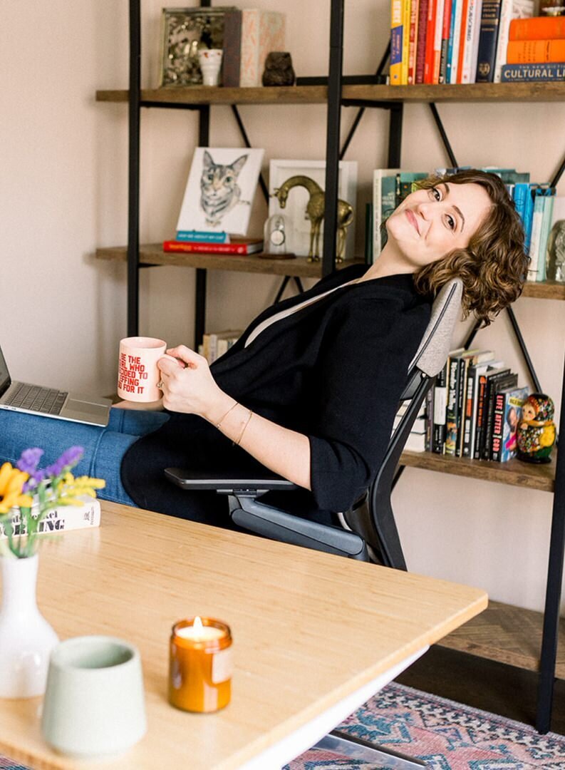 Paige Worthy with coffee mug sitting in an office chair
