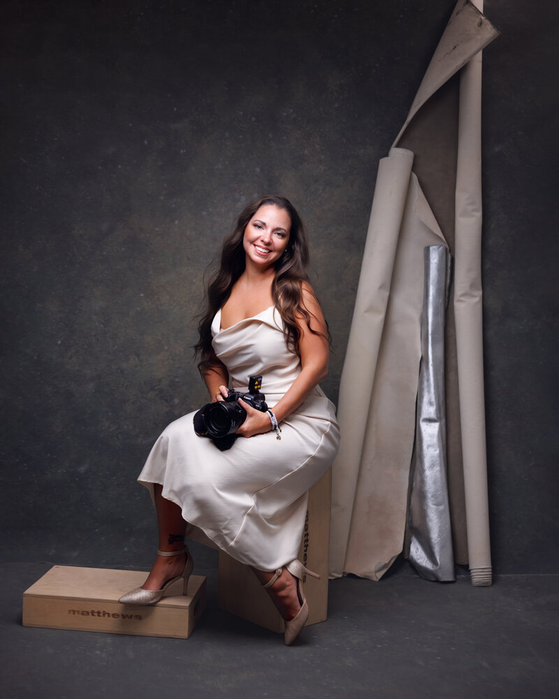 New Jersey Newborn Photographer Sarah Dubas  smiling in an ivory dress with camera in hand