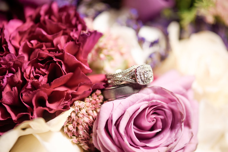 Wedding rings surrounded by pink, red,  and white flowers
