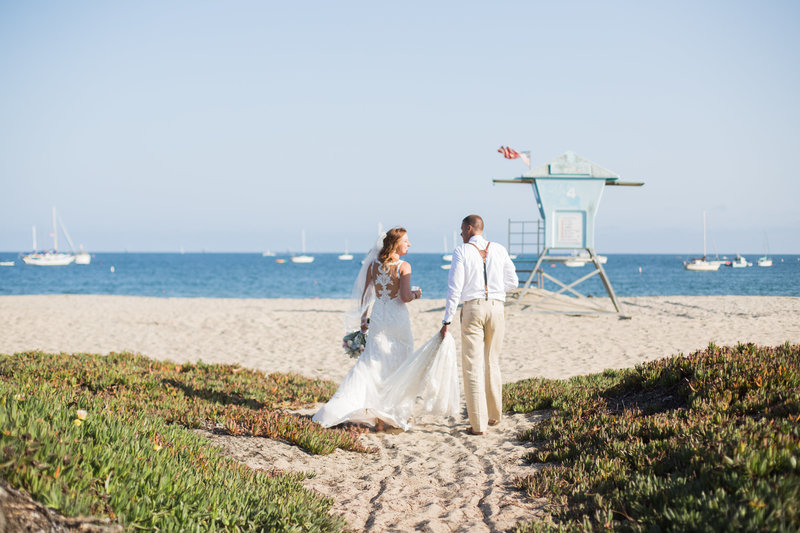 Bride and groom walk on beaches of Santa Barbara after wedding