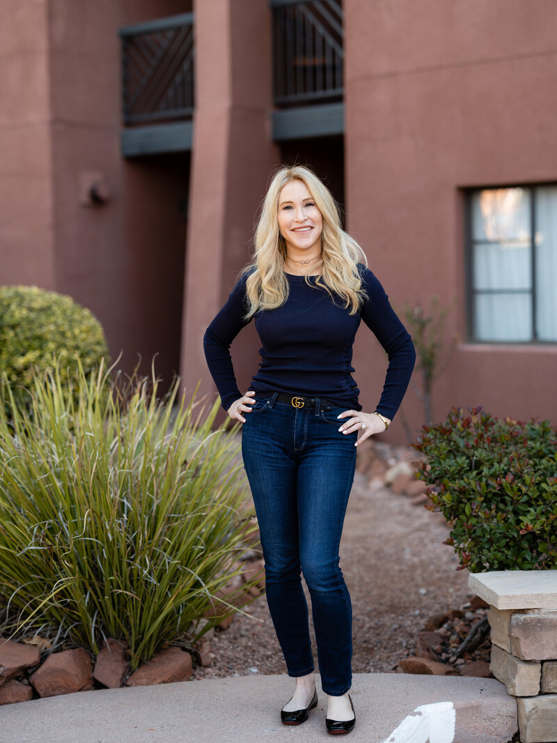 this is lindsay lovell, a real estate investor and coach, standing in front of the camera wearing blue long sleeves and jeans