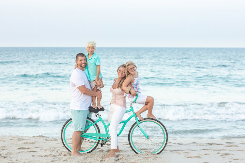 Fun family photo on the beach riding a bike