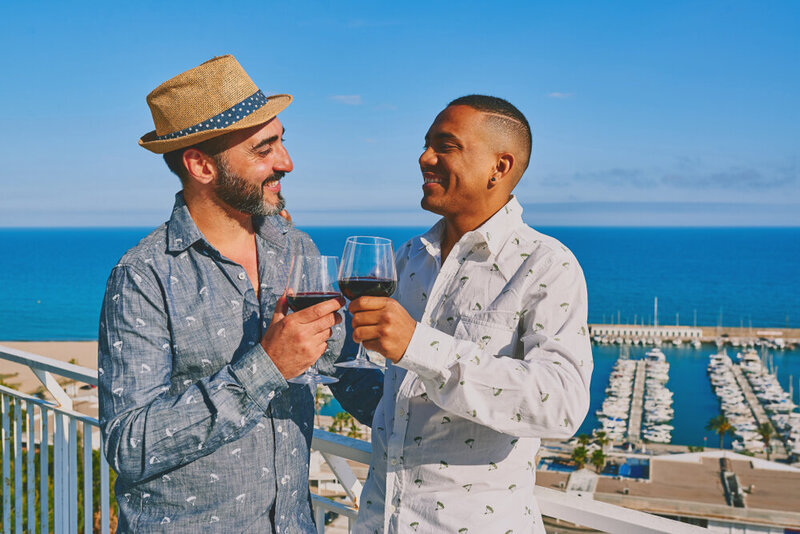 LGBTQ travel gay couple drinking wine vacation passports and palms travel