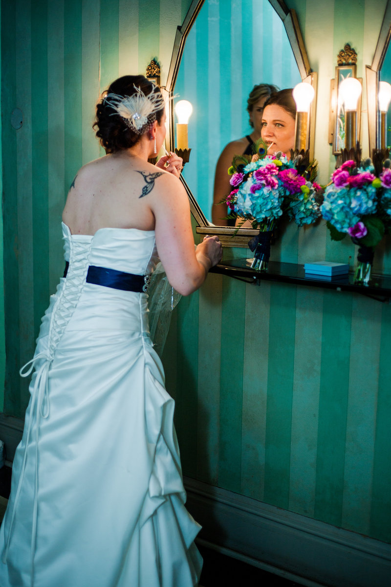Bride checks her makeup in a mirror before her Warner Theatre wedding in Erie, PA