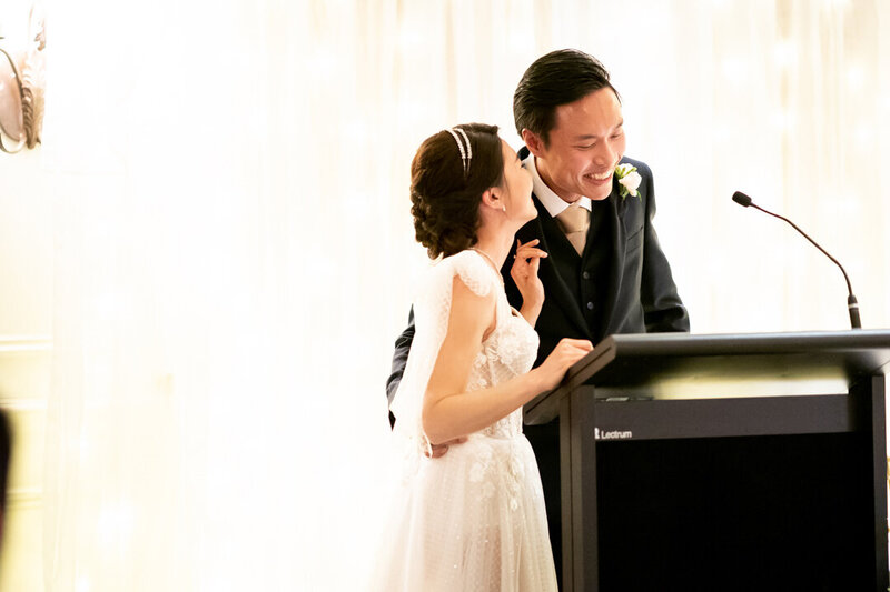Bride and groom laughs as they speak at the reception