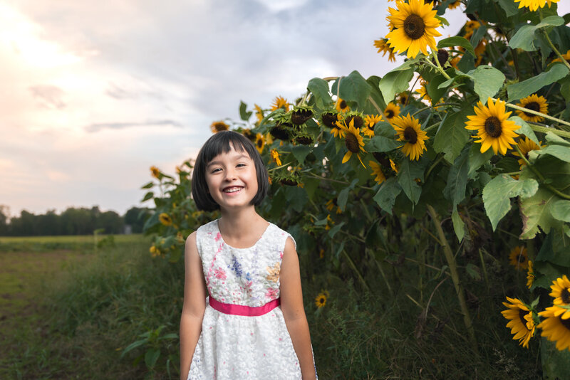 Young asian girl smiling enjoying family photo with sunflowers