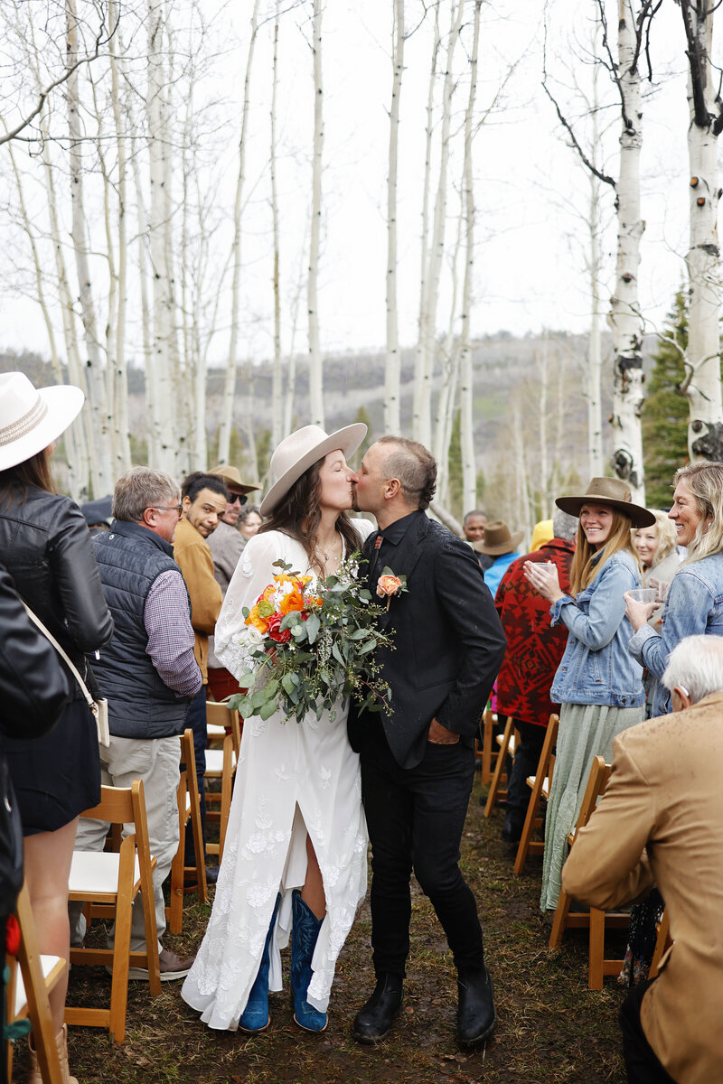 A beautiful bride holds her bouquet and has a cowboy hat on for her aspen, colorado wedding,