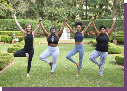Group of women holding hands while doing a yoga pose