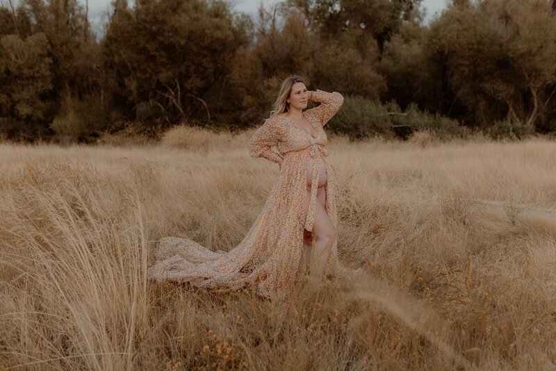 A woman in a long dress standing in a field of tall grass.