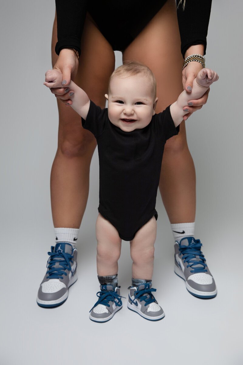 Close up of baby smiling and holding parents hands by baby photographer nj