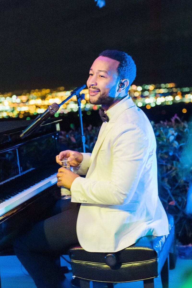 John Legend singing at an intimate outdoor concert during a private luxury event in Reno, with soft lighting and evening sky.