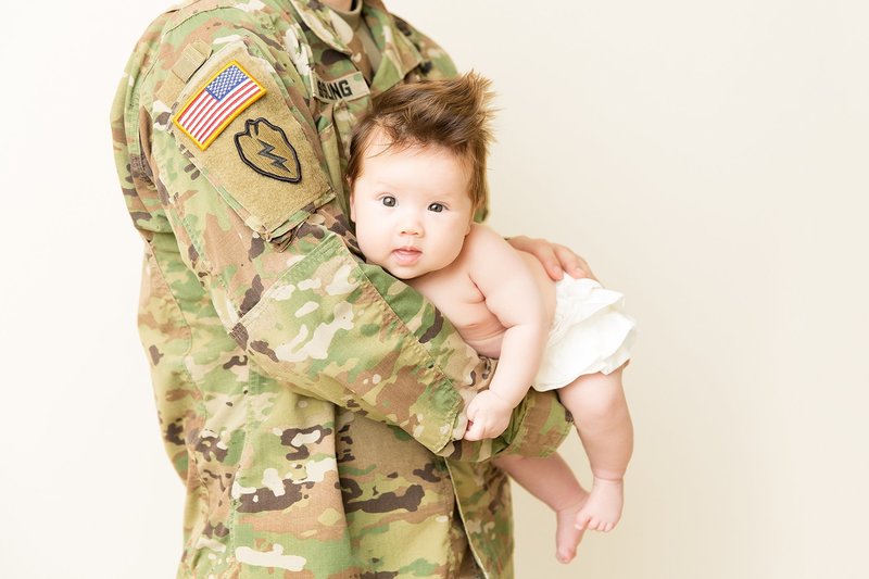 3 month old baby in dads arms with uniform