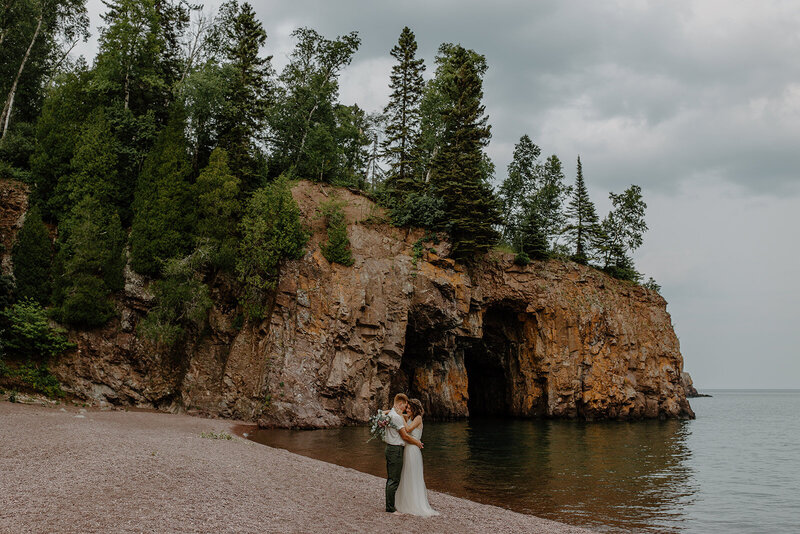 Bride and groom slow dancing on a secret rocky beach near a sea cliff, in Tettegouche State Park