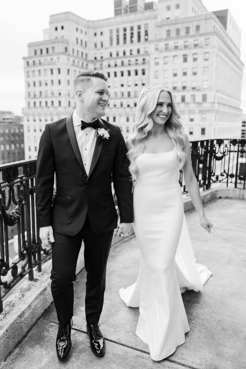 A couple who decided to get married in Philadelphia share a candid moment on a dark gray City Hall background