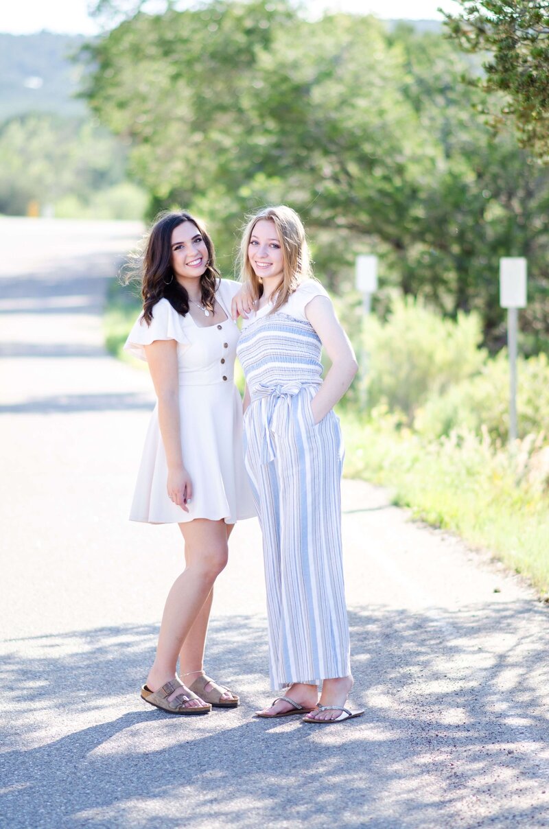 2 girls standing in a road and smiling at the camera