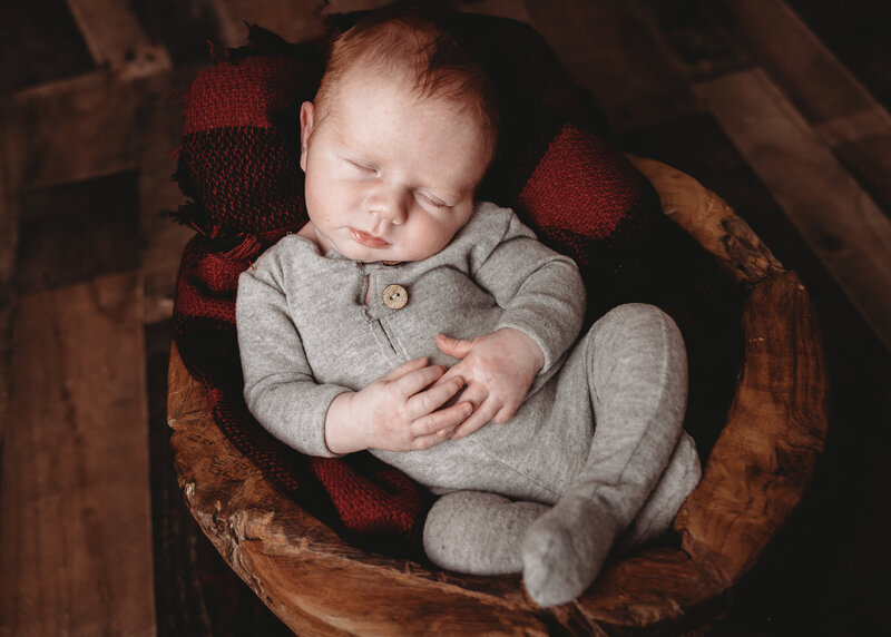A newborn baby asleep in a leather bean bag.