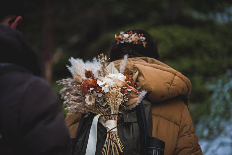 flower bouquet packed in a backpack worn by a bride for a hiking elopement. in norway