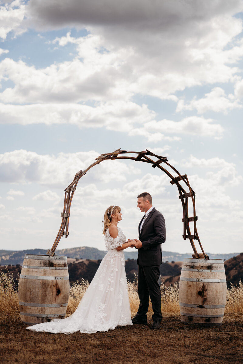 Bride and groom standing under an arch on a beautiful and cloudy day