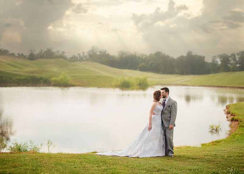 wedding couple kiss in front of lake with gorgeous sky