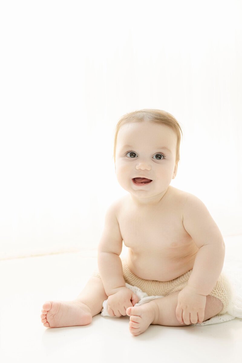 Little baby sitting and smiling taken by baby photographer nj