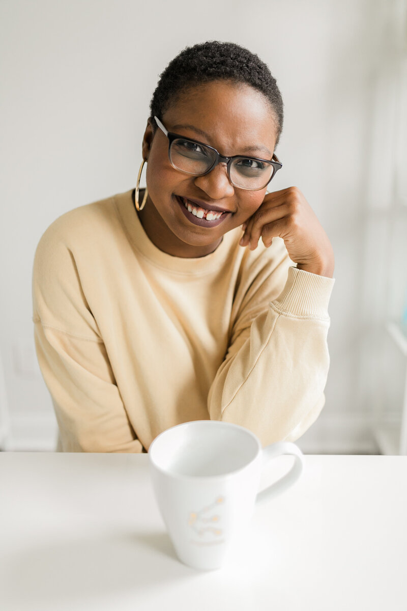A Black woman wearing a yellow sweater smiling at the camera.