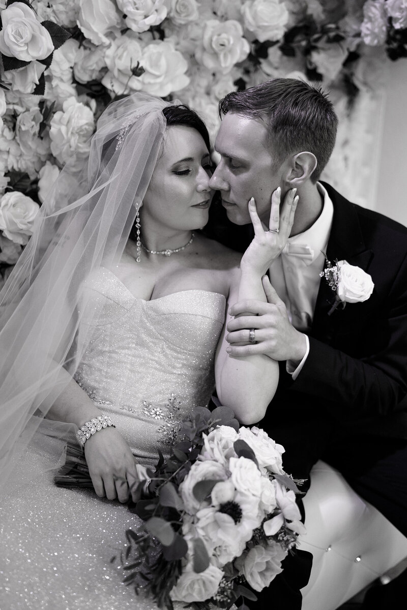 Romantic wedding portrait of a bride and groom cuddled close against a floral rose backdrop, captured by a Colorado wedding photographer.