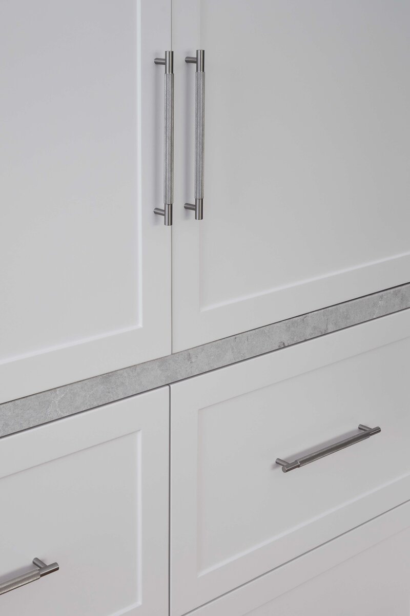 Close-up of custom white kitchen cabinetry with silver handles and stone detail | Melbourne interior design services