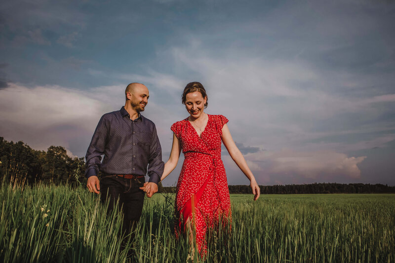 engaged couple walking through barley field