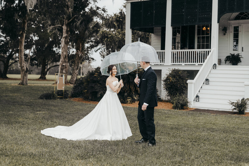 bride and groom with umbrellas at agapae oaks wedding
