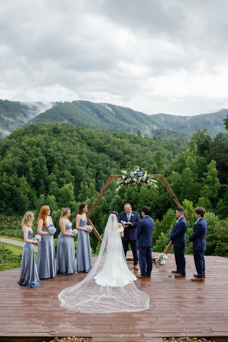 gatlinburg photographers captures ceremony photo at Mountain Mist Farms with the bride and groom surrounded by their wedding party with the Smoky Mountains in the distance and fog rolling through the hills