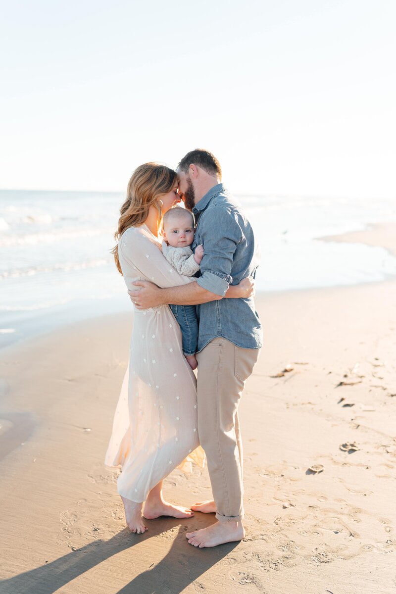 Couple embracing each other at the beach with baby in between