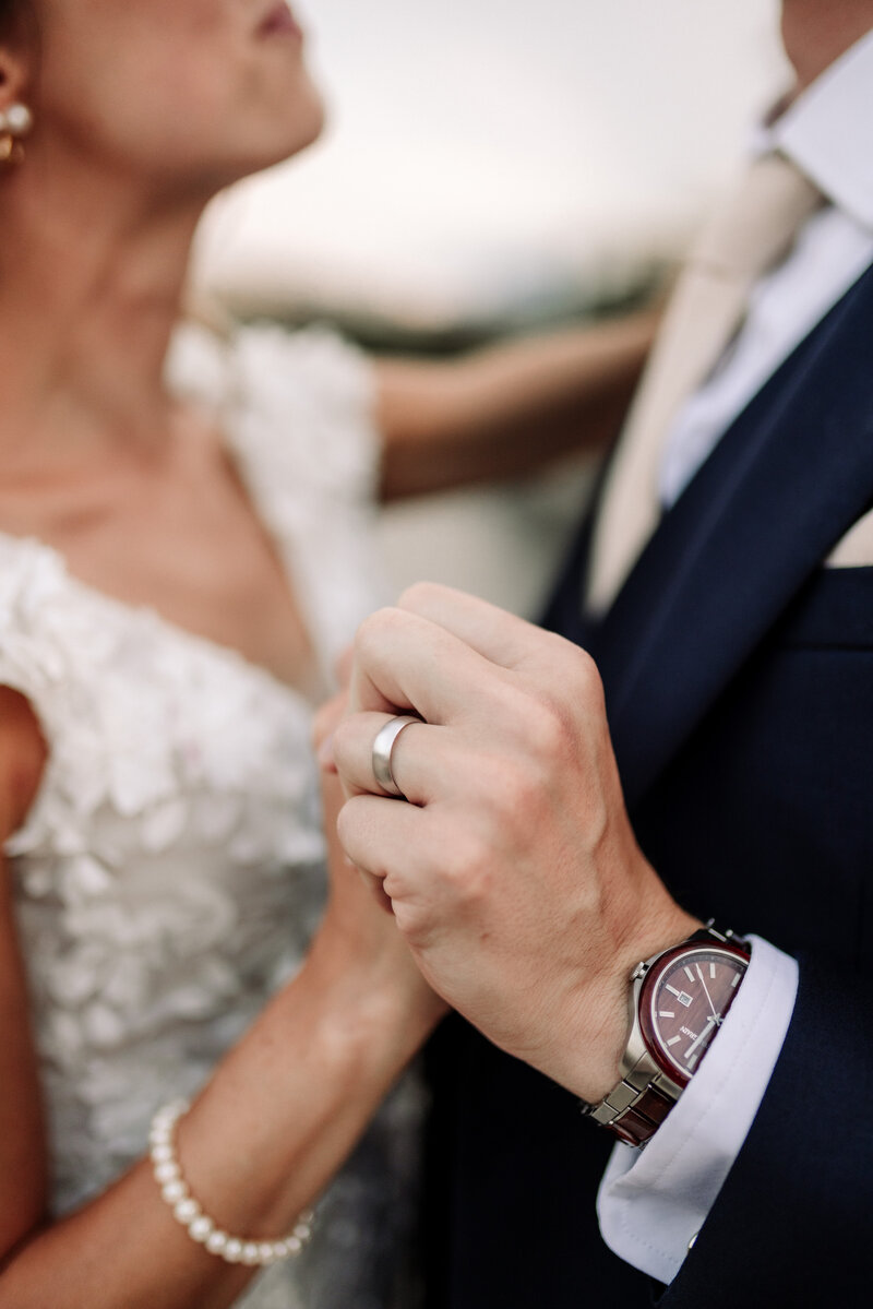 Bride and groom hold hands with wedding bands showing