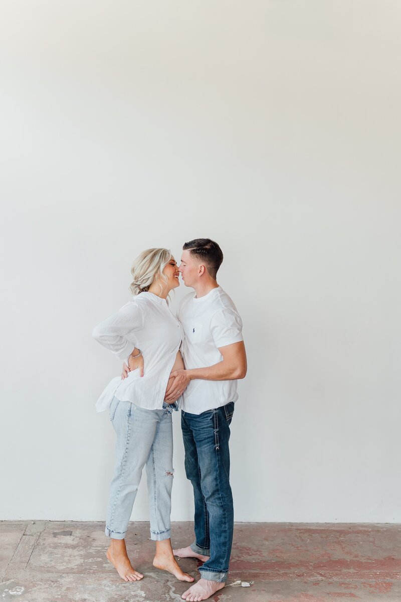 Couple touching noses and embracing baby bump