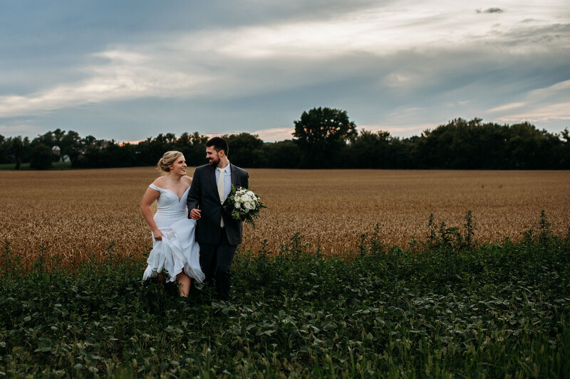 Bride and groom running out of a field