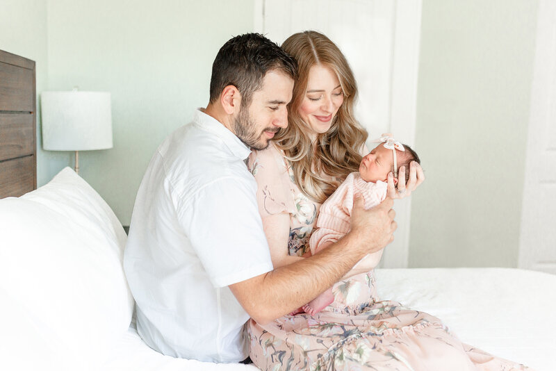 Family of 3, Mom, Dad and Baby on bed during luxury newborn photos taken by Ann Arbor Newborn Photographer