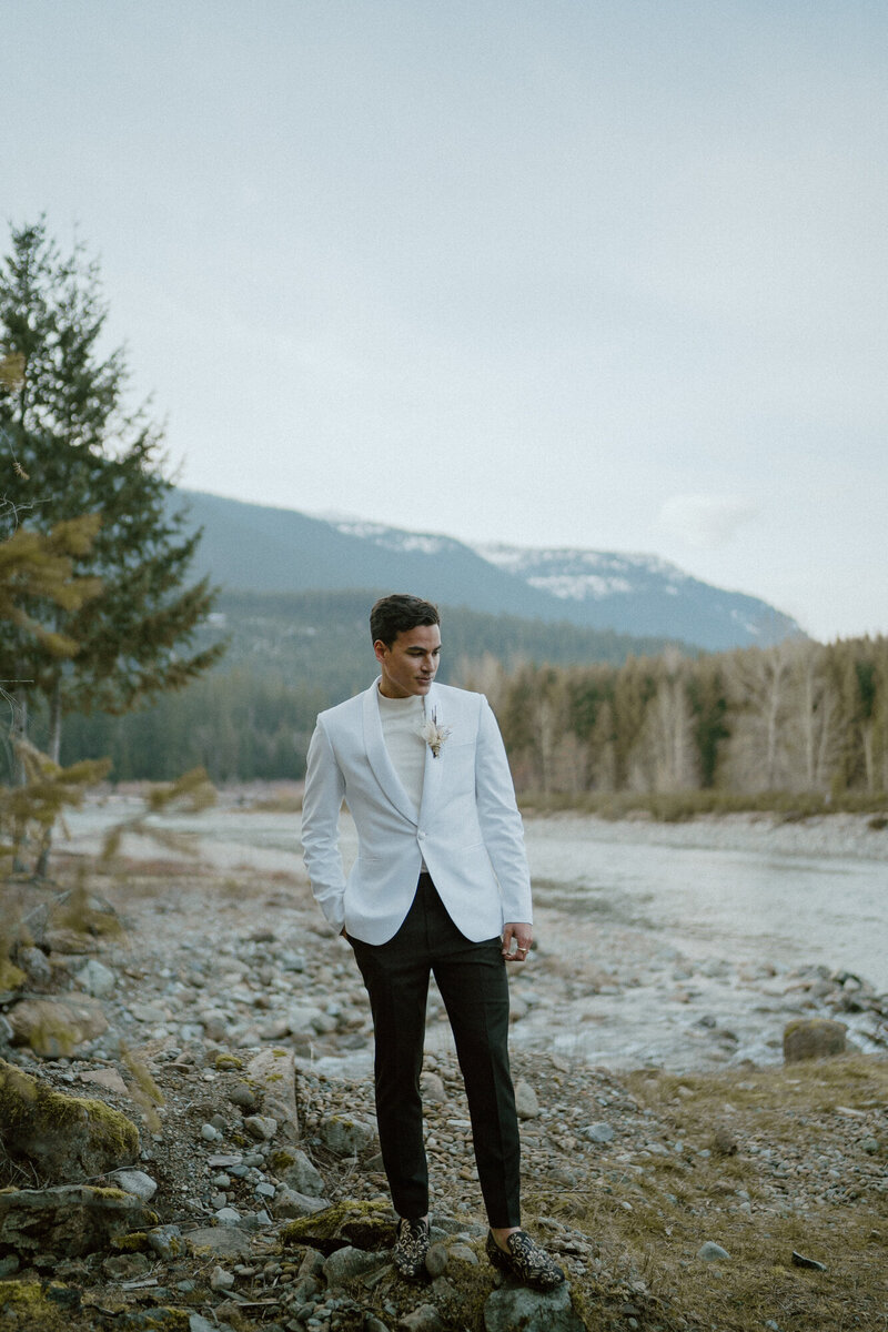 handsome groom near river and mountain