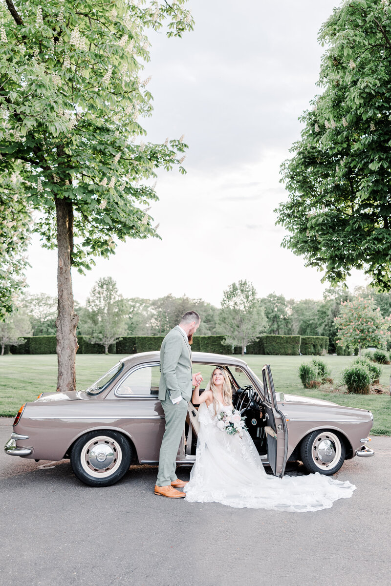groom helping bride out of a vintage car
