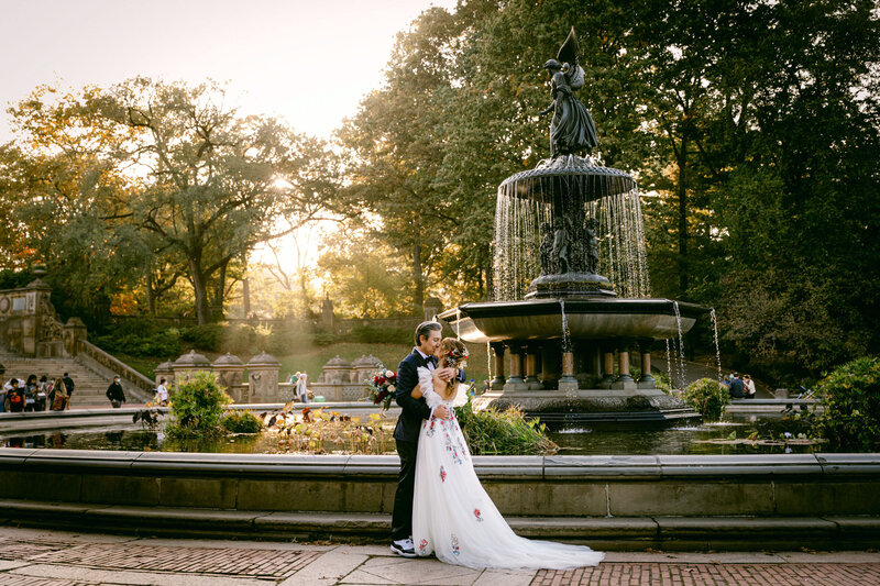 A bride and groom kiss at the Bethesda Fountain