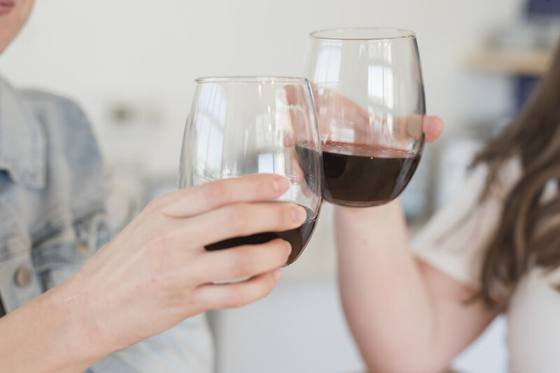 two hands toasting wine glasses