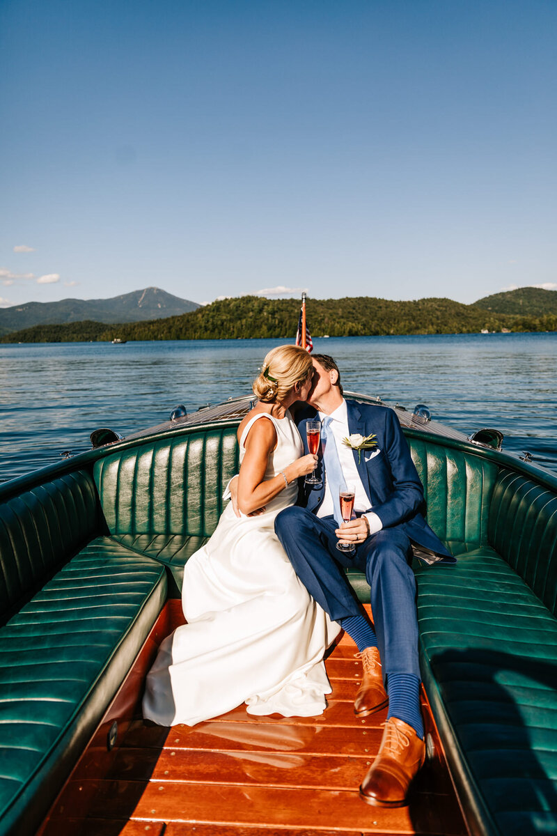 bride and groom kissing on a boat at lake placid new york