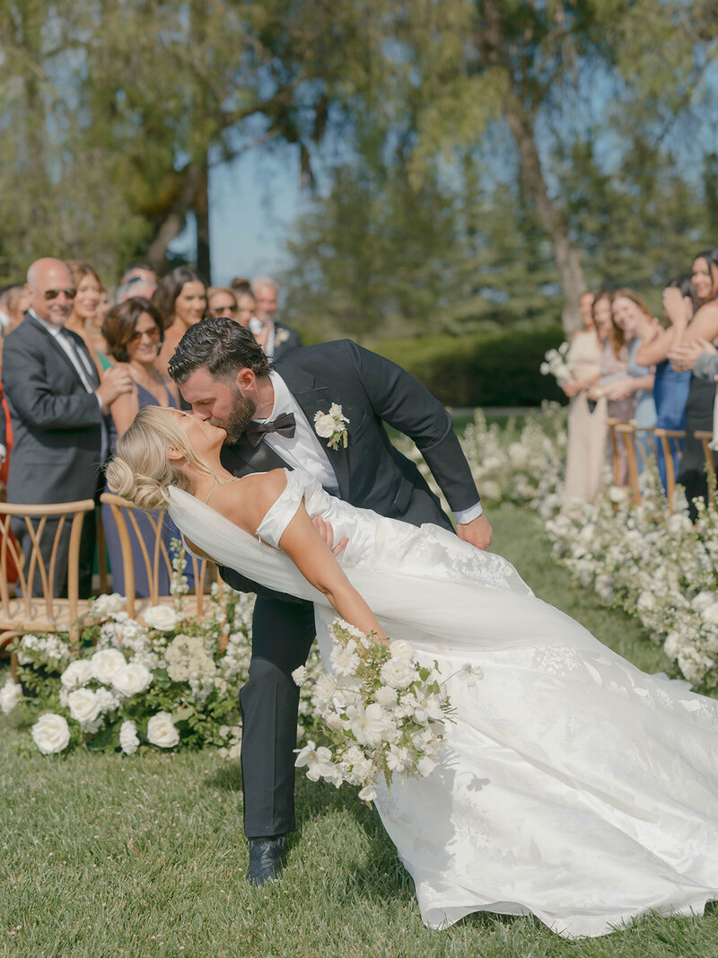 Wedding reception tables set up in an outdoor arched corridor overgrown with ivy