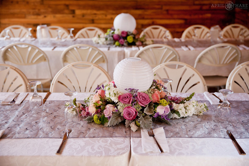 Pretty Long White Tables with purple and pink florals at Mountain View Ranch Barn Reception