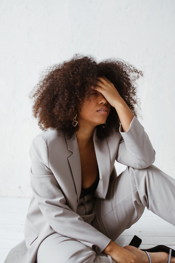 A woman in a grey suit looking overwhelmed. Representing someone in NYC who could benefit from stress management counseling in Manhattan. If you are overwhelmed like that a stress management counselor in Manhattan can help!